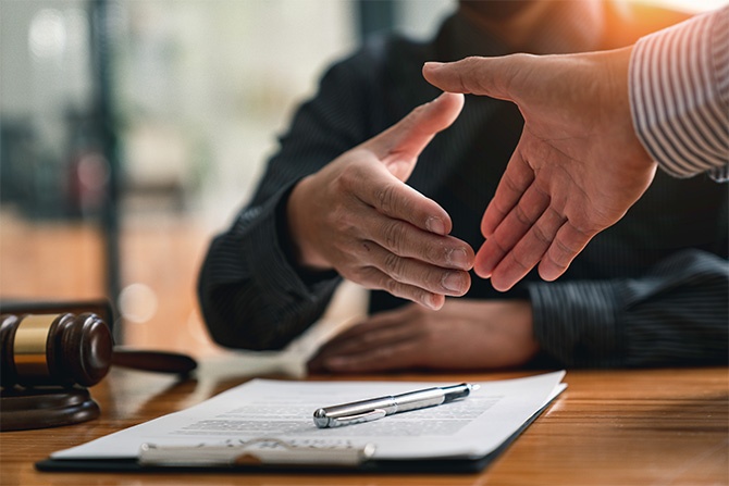 Two people shaking hands over a legal document